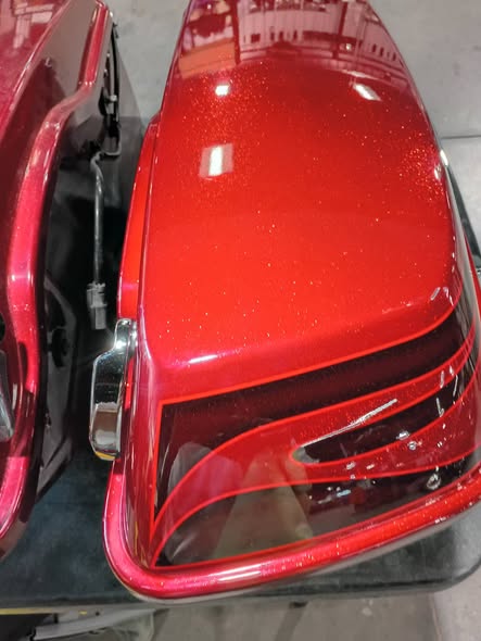 Glossy red motorcycle saddlebag after paint restoration
